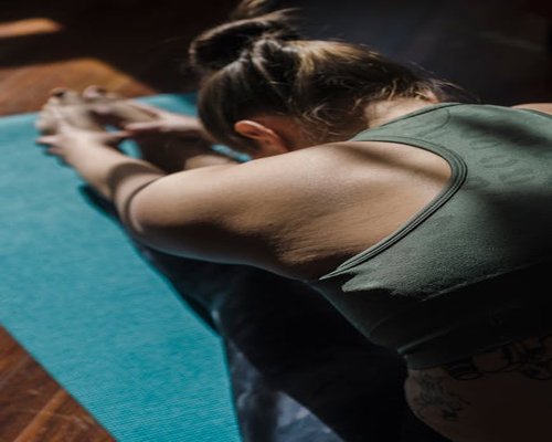 Person stretching on a mat with moody lighting